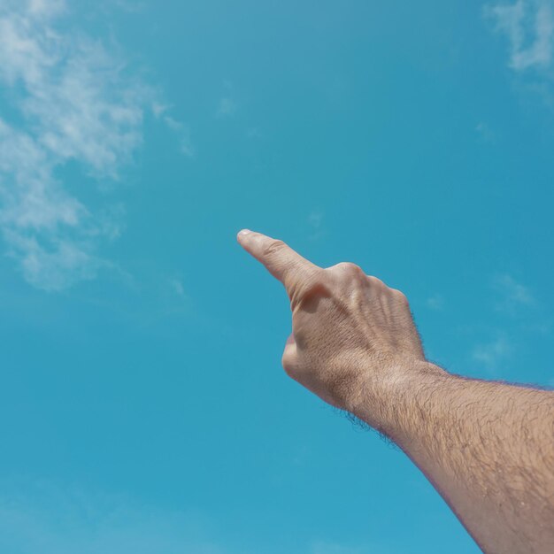 Foto mano arriba gesticulando en el cielo azul, sentimientos y emociones