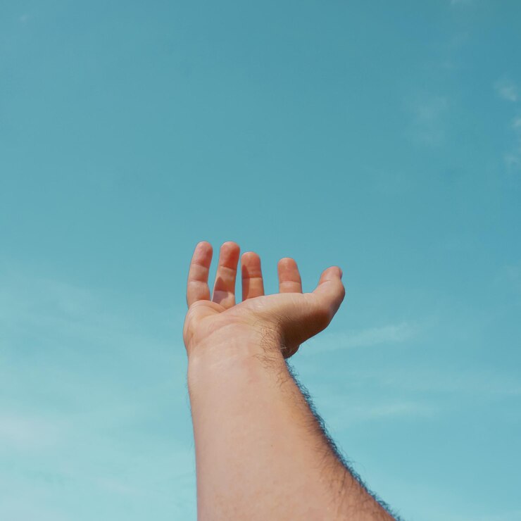 Foto mano arriba gesticulando en el cielo azul, sentimientos y emociones