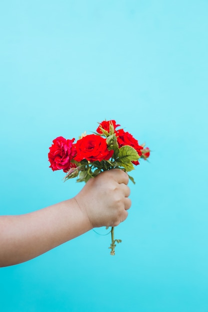 Mano de arte de moda de un niño pequeño con ramo de rosas