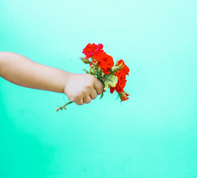 Foto mano de arte de moda de un niño pequeño con ramo de rosas