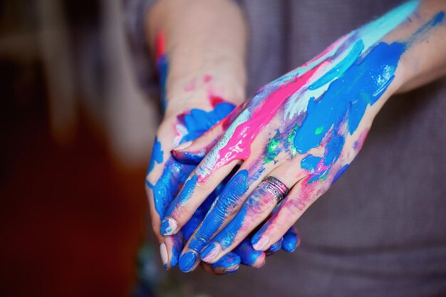 La mano del artista con un pincel fino sumergió pinturas acrílicas fluorescentes brillantes Azul rosa turquesa El concepto de inspiración creativa