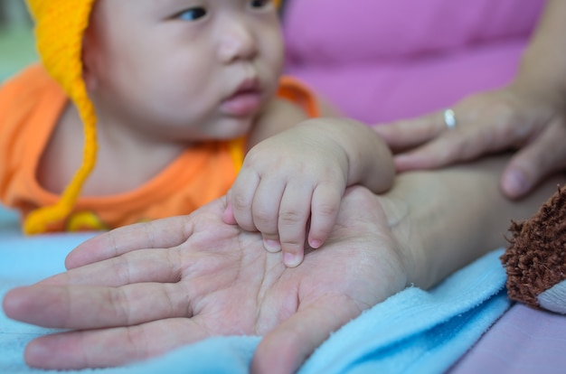 Mano asiática del bebé en la mano de las madres