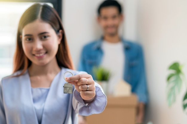 Foto mano asiática joven del primer que sostiene el llavero de la casa