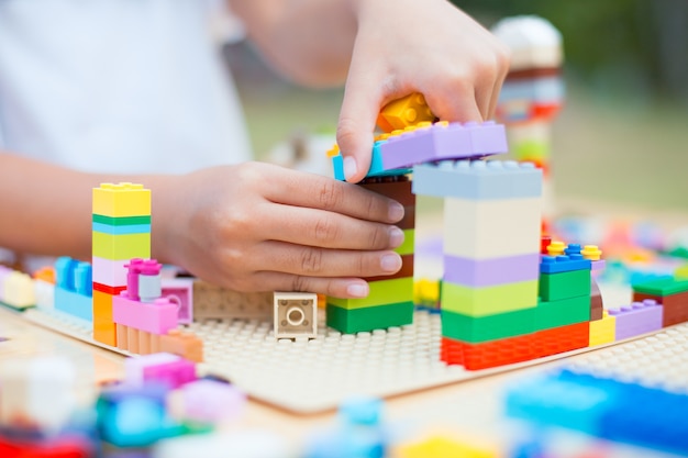 Mano asiática de la niña del pequeño niño que juega con los bloques coloridos.