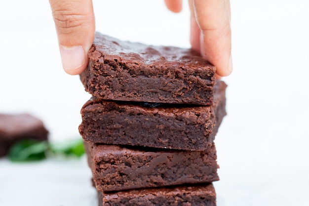 Mano asiática recogiendo un brownie de chocolate