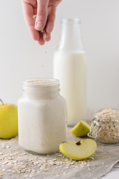 Mano asperja harina de avena en un vaso con yogur