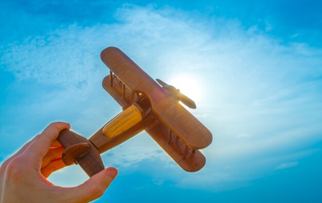 La mano con un avión de madera en el fondo de la puesta de sol