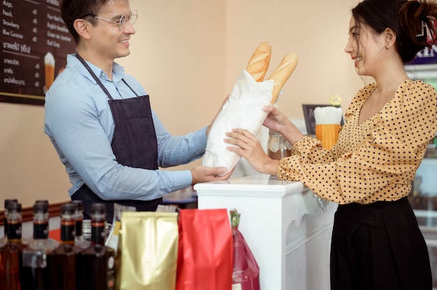 Mano de baristas tomando una taza de café caliente y panadería para ofrecer al cliente en la cafetería.