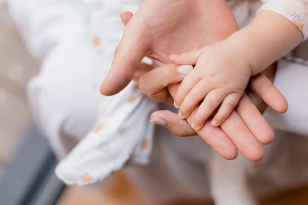 La mano de un bebé es sostenida por un hombre y una mujer sosteniendo la mano de un bebé.