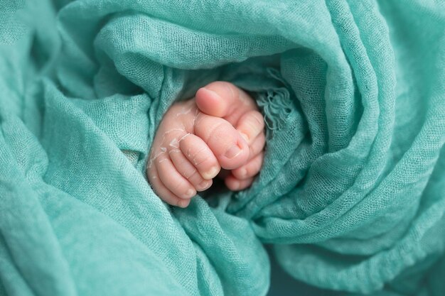 La mano de un bebé está envuelta en una manta verde.