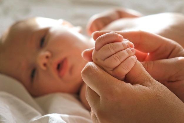 Mano del bebé en las manos de la madre en la palma de la mano Padres felices sosteniendo a su bebé recién nacido dedos diminutos de cerca Concepto de nacimiento de la familia de maternidad Mujer tocando la mano del bebé Mamá y su hijo