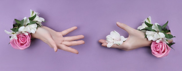 Mano de belleza con flores en un agujero en un papel morado