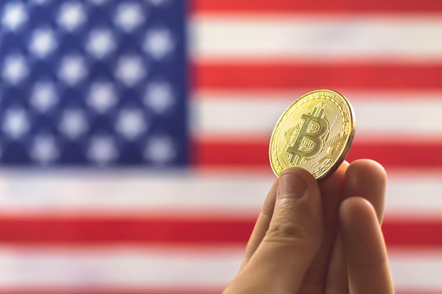 Mano con bitcoin y la bandera de estados unidos en el fondo