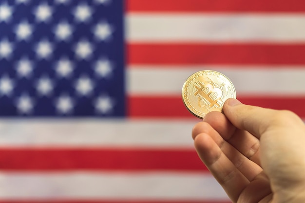 Mano con bitcoin y la bandera de Estados Unidos en el fondo. Foto de concepto de criptomoneda y Estados Unidos de América