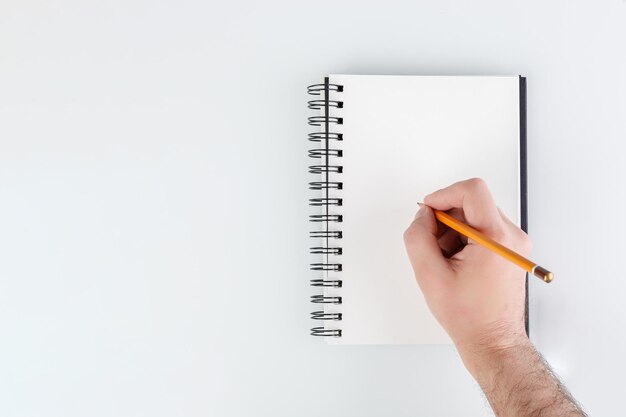 mano de bloc de notas de negocios sosteniendo un lápiz en un primer plano de fondo blanco