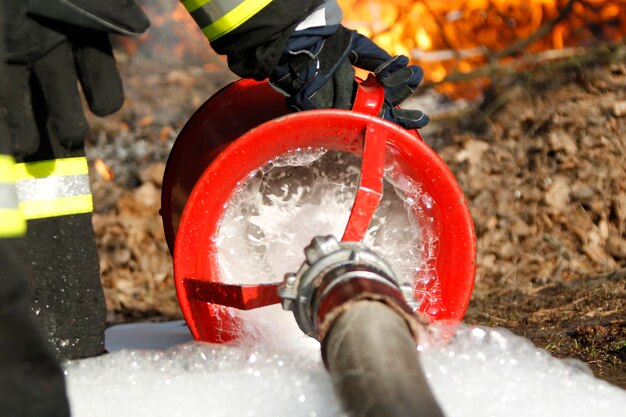 Foto la mano del bombero sostiene una manguera contra incendios para extinguir un incendio. extinguir el fuego. manguera de fuego