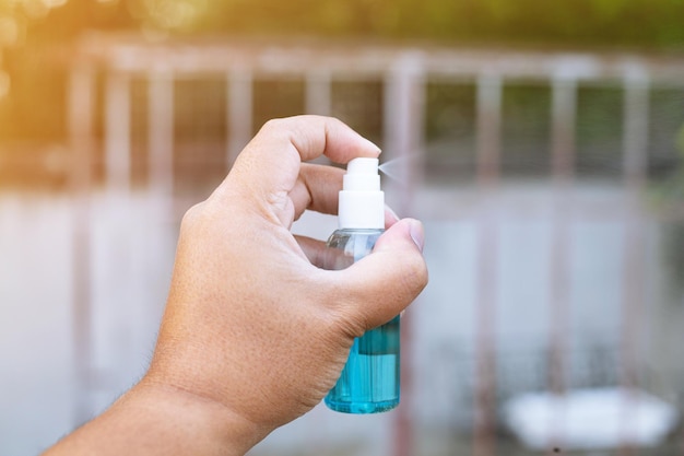 La mano con una botella de spray de alcohol covid-19