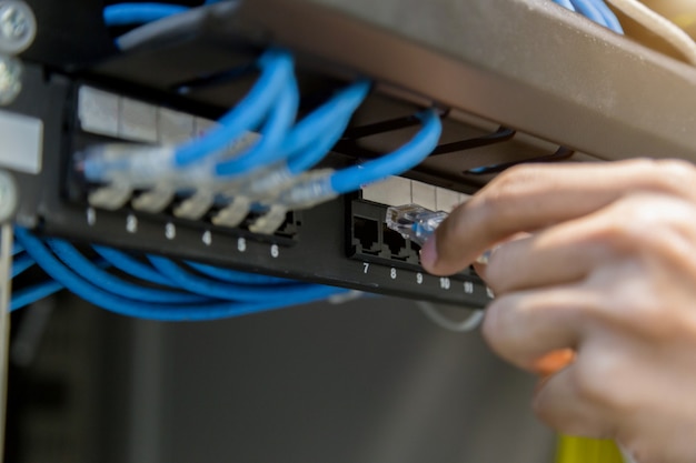 Mano con cables de red conectados a servidores en un centro de datos.