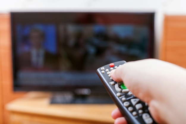 La mano cambia los canales de TV con noticias