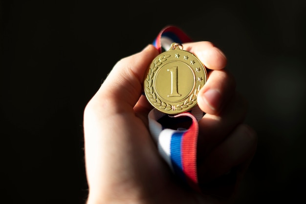 Mano de Campion con una medalla de oro, concepto afortunado ganador