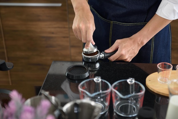 Mano cercana del barista usando manipulación para preparar café en la cafetería