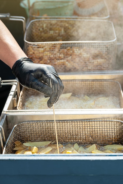 La mano del chef comprueba la calidad de las patatas fritas Comida callejera