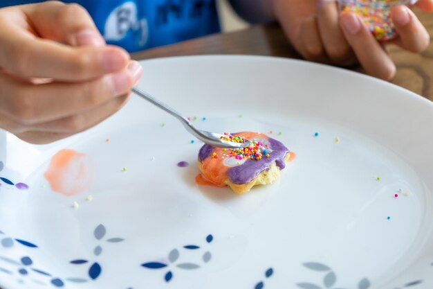Foto la mano de la chica decorando la superficie de la galleta con azúcar de colores