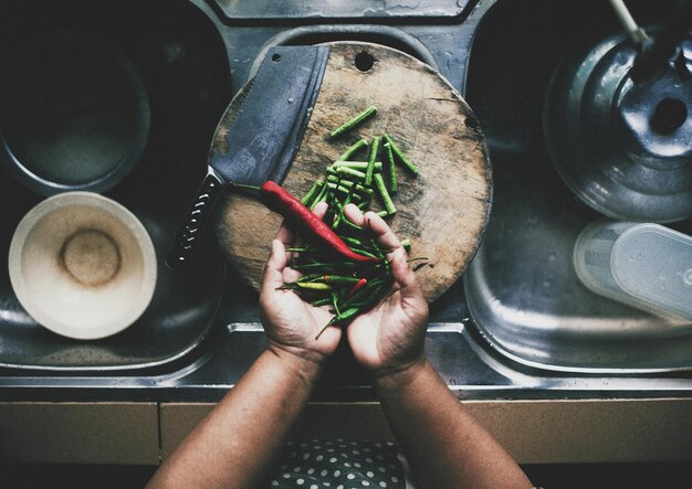 La mano con chile y frijoles verdes sobre el fregadero