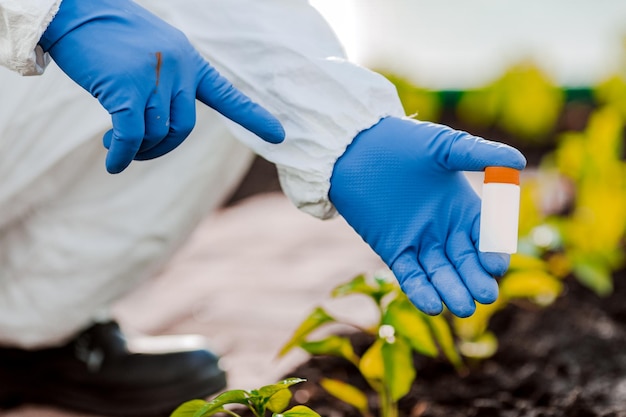 La mano del científico sostiene un frasco de muestras de tierra para su análisis.