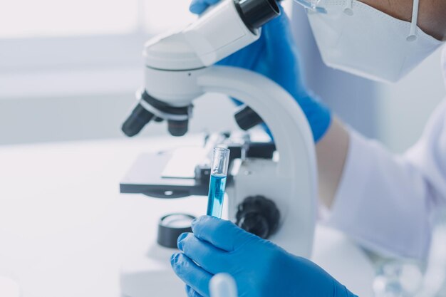 Foto mano de científico con tubo de ensayo y matraz en fondo de bandera azul de laboratorio de química médica