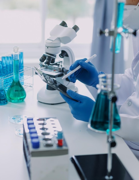 Foto mano de científico con tubo de ensayo y matraz en fondo de bandera azul de laboratorio de química médica