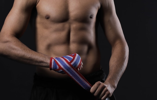 Mano de combate masculino de primer plano con vendas. Los puños del luchador se aprietan antes de una pelea o un entrenamiento en un gimnasio deportivo.