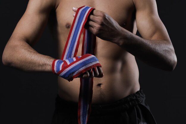 Mano de combate masculino de primer plano con vendas. Los puños del luchador se aprietan antes de una pelea o un entrenamiento en un gimnasio deportivo.