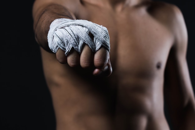 Mano de combate masculino de primer plano con vendas. Los puños del luchador se aprietan antes de una pelea o un entrenamiento en un gimnasio deportivo.