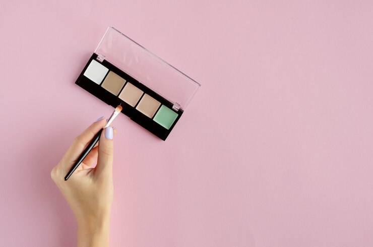 Foto mano con composición de paleta de sombras de maquillaje