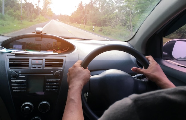 Mano conduciendo un coche en la carretera de fondo borroso