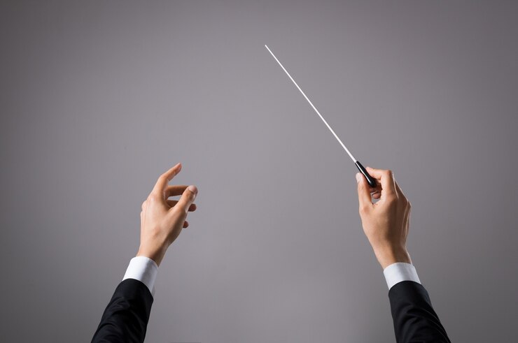 Foto mano de conductor de concierto con bastón aislado en gris