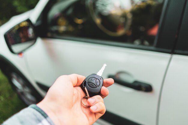 Foto mano del conductor sosteniendo un mando a distancia inalámbrico llaves para abrir el coche