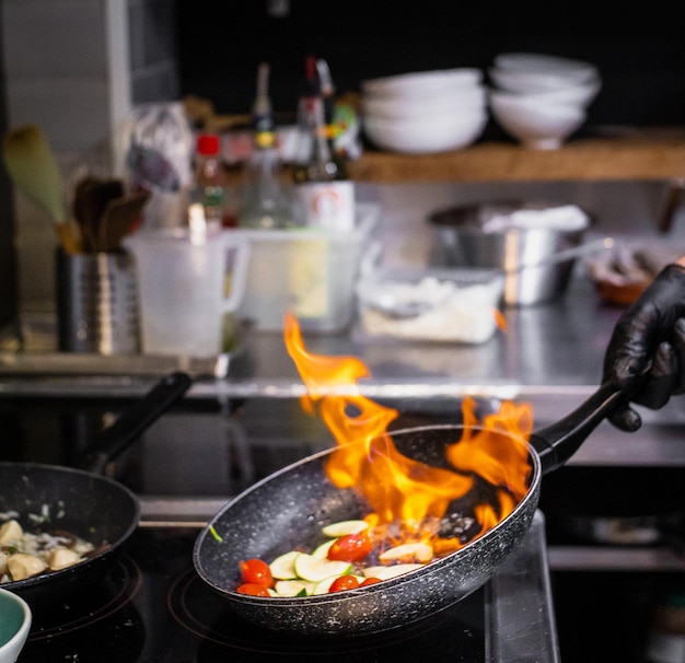 Foto mano cortada del chef cocinando comida en la cocina