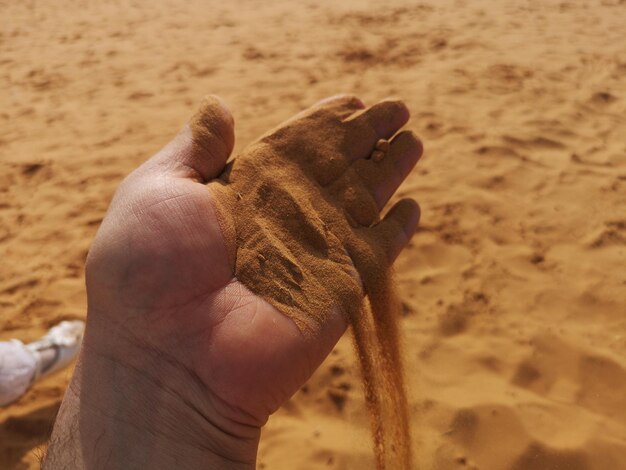 Foto la mano cortada derramando arena en la playa