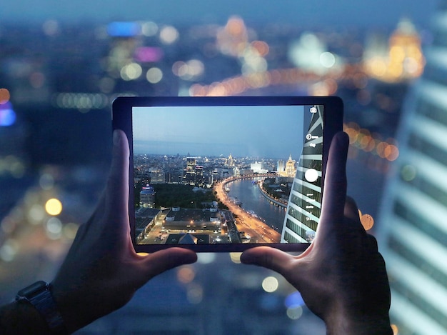Mano cortada de un hombre fotografiando la ciudad a través de una tableta digital