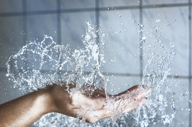 Mano cortada de un hombre salpicando agua en el baño