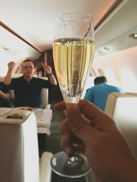 Foto mano cortada de un hombre sosteniendo una bebida en un avión