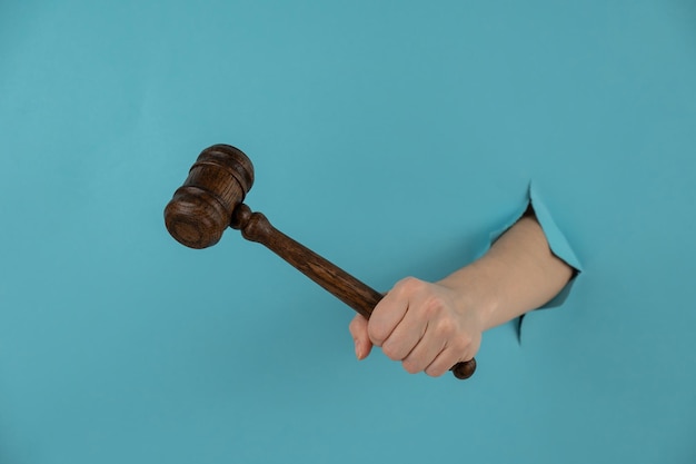 Foto mano cortada de un hombre sosteniendo un martillo contra un fondo azul