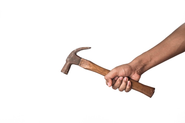 Mano cortada de un hombre sosteniendo un martillo contra una pared blanca