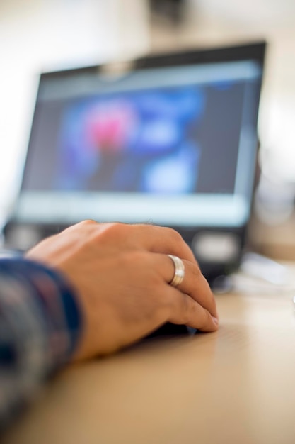 Mano cortada de un hombre usando una computadora en la oficina