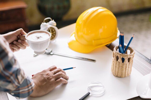 Foto la mano cortada de un ingeniero tomando café en la oficina