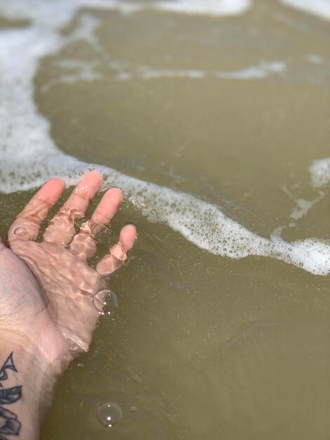 Foto mano cortada en el mar en la playa