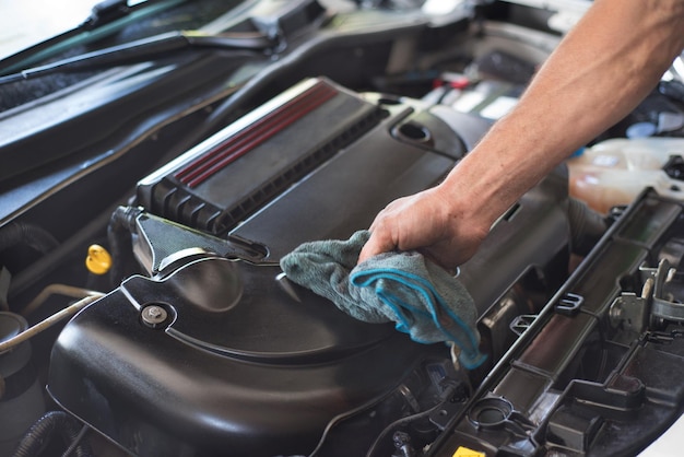 Mano cortada de un mecánico reparando el motor de un coche en un garaje