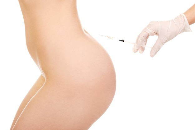 La mano cortada del médico inyectando a una mujer desnuda en la espalda contra un fondo blanco